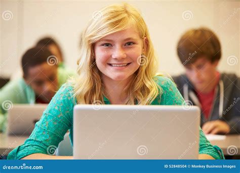 Female High School Student At Desk In Class Using Laptop Stock Photo