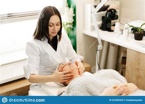 A Cosmetologist Does A Massage Procedure With A Female Face In A