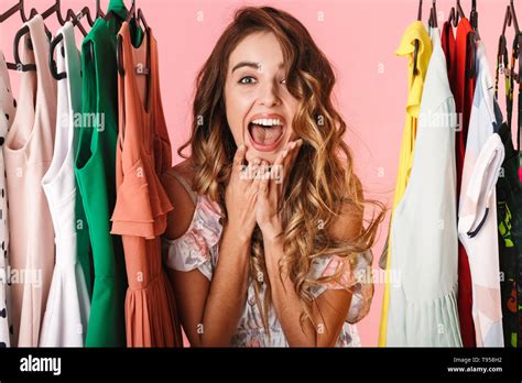 Photo Of Excited Woman In Dress Standing Inside Wardrobe Rack Full Of Clothes Isolated Over Pink