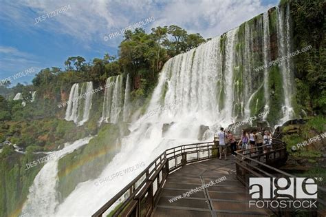 Metal Walkway Leading To Iguazu Falls With A Rainbow Is Visible Over