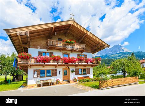 Traditional Alpine House With Balconies Decorated With Flowers In Going