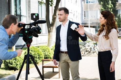 Cameraman And News Reporter With Microphone Interviewing Businessman