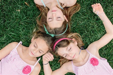 Three Young Sister Laying On Grass With Their Heads Together By