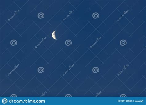 Bright White Crescent Moon Against A Cloudless Blue Sky Stock Photo