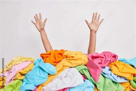 Human Hands Reaching Out From Big Pile Of Colorful Unfolded Clothes