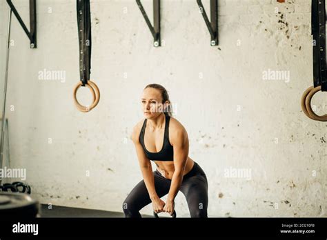 athletic woman exercising with kettle bell while being in squat position muscular woman doing