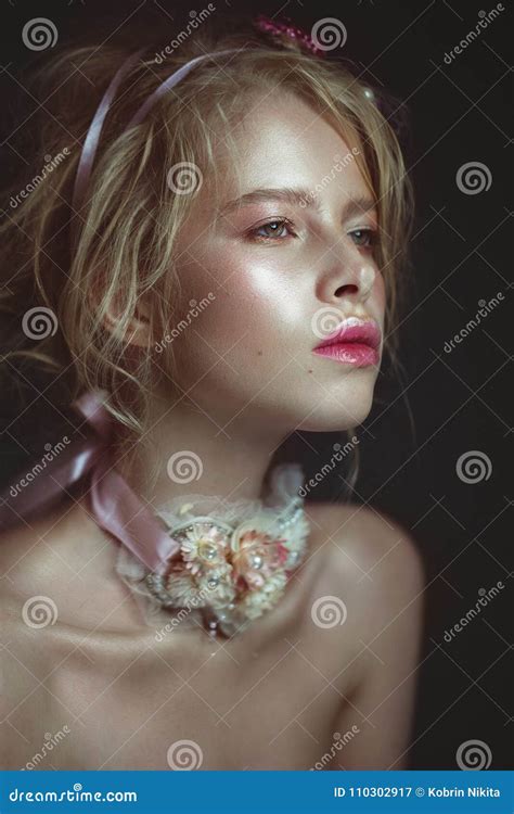 Красивая белокурая девушка моды с цветками на шеи и в ее волосах