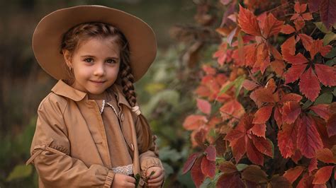 Cute Little Girl Is Standing Near Red Leaves Plant Wearing