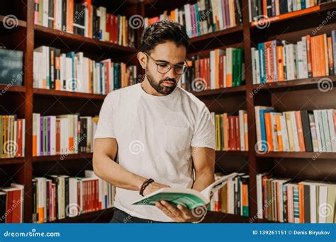 Portrait Of Handsome Young Man Reading Book At Library Knowledge And