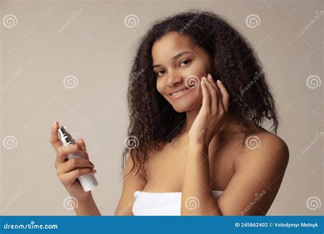 Portrait Of Young Beautiful Woman Applying Moisturizing Cream Taking Care After Skin Over Grey