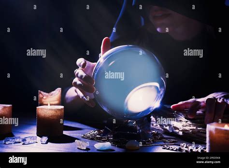Soothsayer using crystal ball to predict future at table in darkness