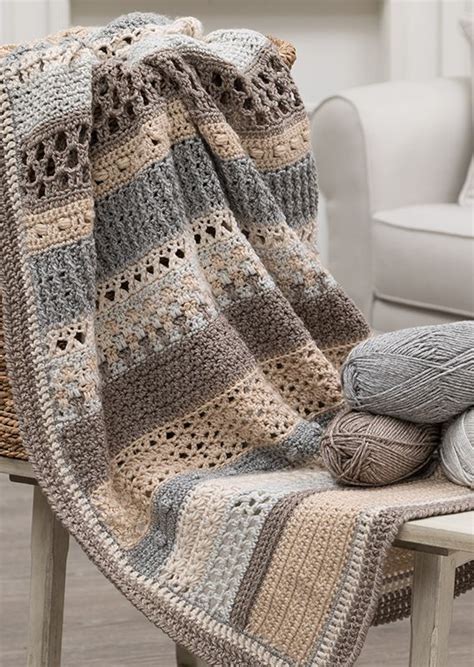 A Crocheted Blanket Sitting On Top Of A Wooden Bench