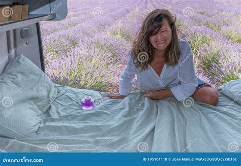 Camper In Lavender Field Woman Laughing As She Climbs Into Bed Stock