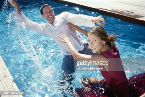 Couple In Swimming Pool With Clothes On Having Water Fight Photo