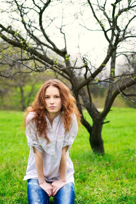 Beautiful Red Haired Girl Sitting On Grass Stock Image