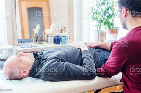 Male Patient Receiving Cranial Sacral Therapy Lying On The Massage