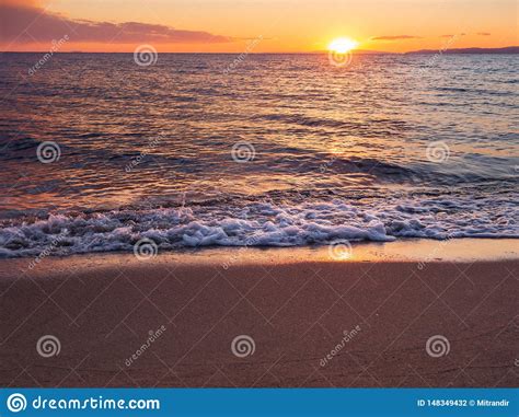 Sunset On A Beautiful Empty Sandy Beach Foamy Waves Stock Photo