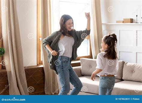 feliz y emocionada madre e hija bailando en la sala de estar moderna imagen de archivo imagen