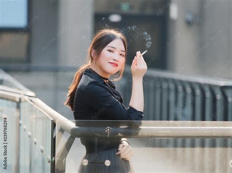 Portrait Of Beautiful Chinese Girl In Black Dress Smoking A Cigarette