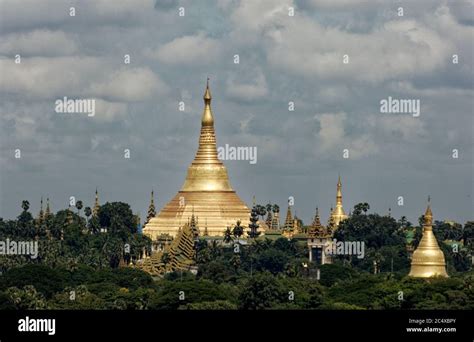The Historic Golden Shwedagon Pagoda And Stupas Over The Treeline In