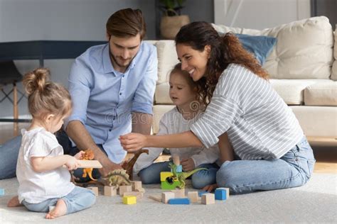 Happy Parents With Two Little Daughters Playing With Toys Stock Photo