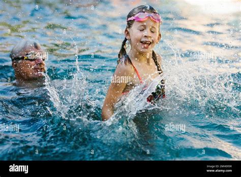 Grandpa Plays And Splash With Granddaughter In Swimming Pool Stock