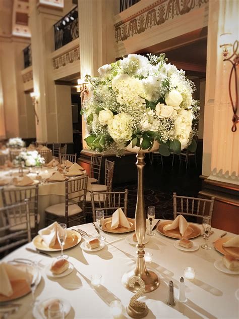 An Elegant Centerpiece With White Flowers Sits On A Table In The Middle