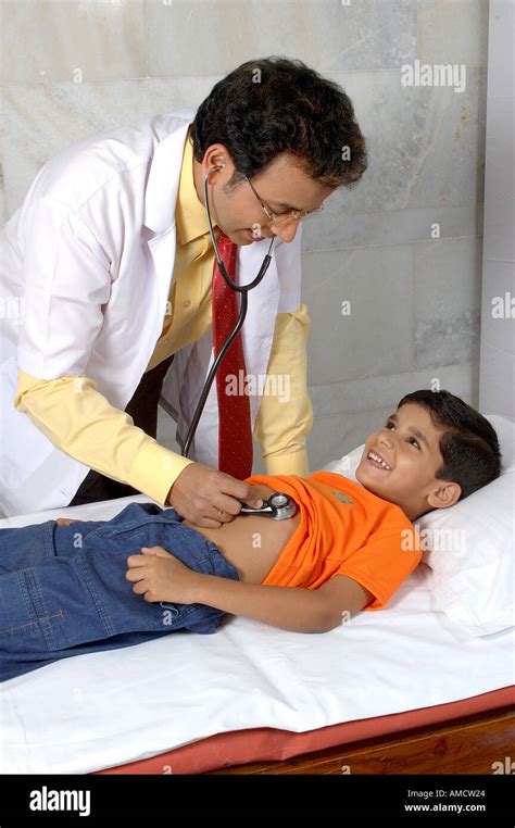 Indian Doctor Checking Small Boy Patient With Stethoscope In Clinic