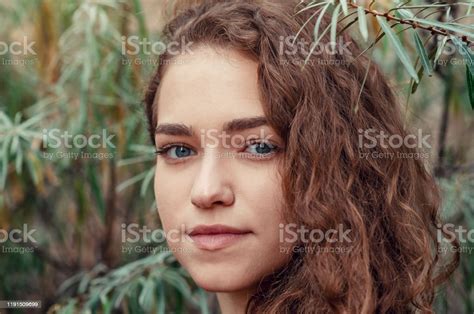 Portrait Of Girl With Brown Curly Hair On Background Of Green Bush Sea