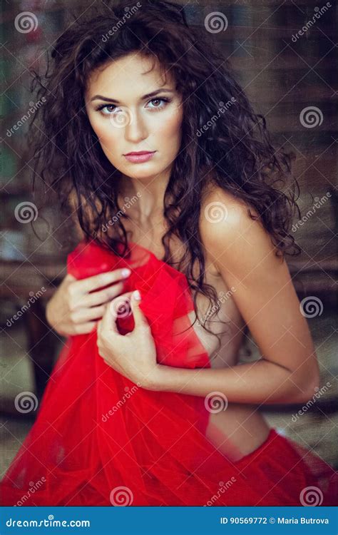 Sensual Very Beautiful Curly Girl In A Red Dress Sitting On Stock Photo