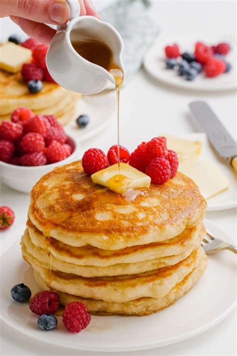 A Stack Of Pancakes With Syrup Being Drizzled Over Them And Topped With