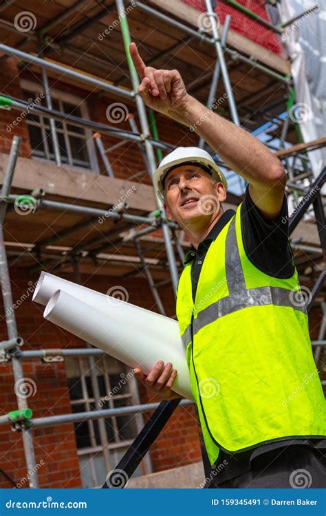 Male Builder Foreman Architect On Building Site Pointing With Plans