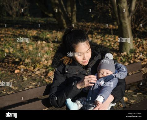 Happy Asian Young Mother Walking With Baby Outdoors In The Park During