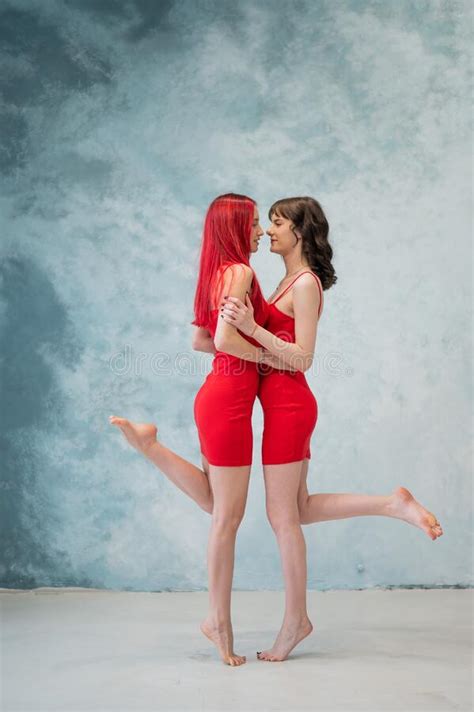 full length portrait of two tenderly embracing women dressed in identical red dresses lesbian