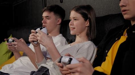 Three Teenagers With Joysticks Play Video Games On The Console Sitting