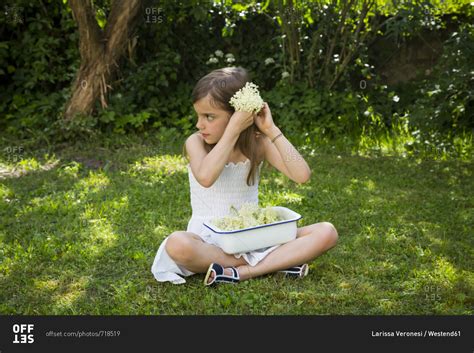 Little Girl Sitting On Meadow In The Garden With Bowl Of Picked