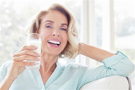 mature woman smiling with drink 1 by science photo library