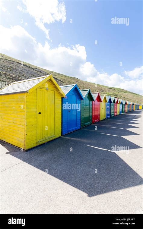 Row Of Brightly Coloured Wooden Beach Huts Along The West Cliff