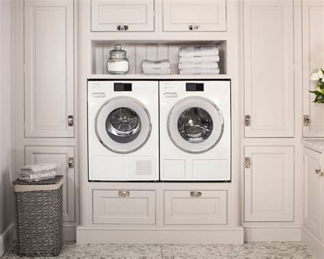 a washer and dryer in a white laundry room with built - in cabinets