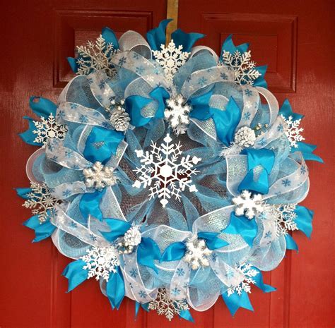 A Blue And White Snowflake Wreath Hanging On A Red Door With Ribbon