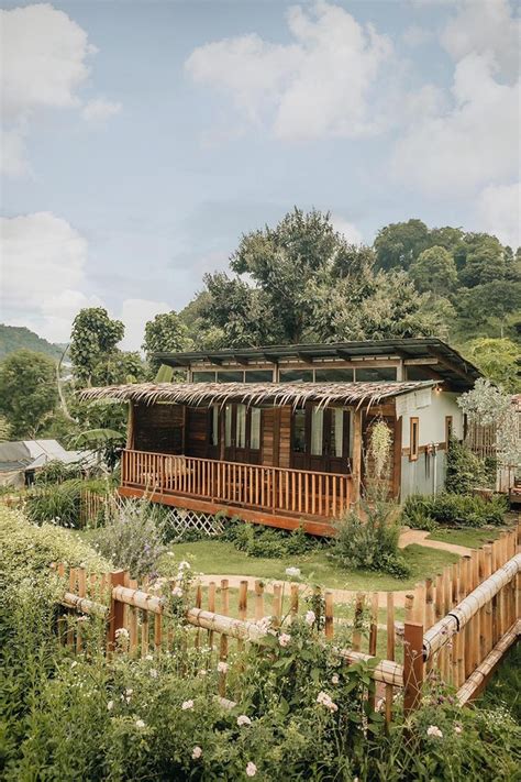 A Small Wooden House Sitting In The Middle Of A Lush Green Field Next