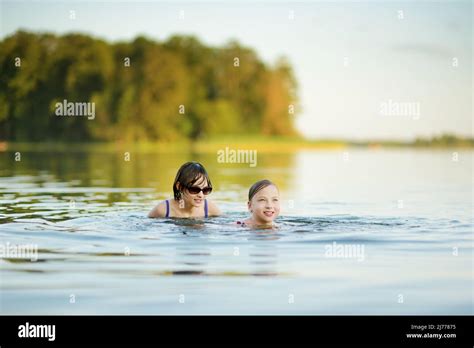 Two Teen Sisters Having Fun On A Sandy Lake Beach On Warm And Sunny