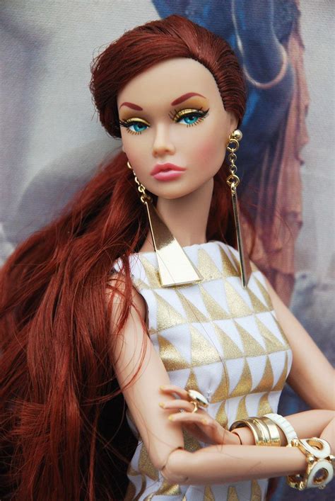 a doll with long red hair and gold jewelry on it s head wearing a white dress