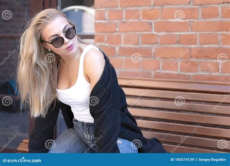 Portrait Of A Blonde With Her Hair Dressed In Blue Jeans A White T Shirt And A Black Sweater