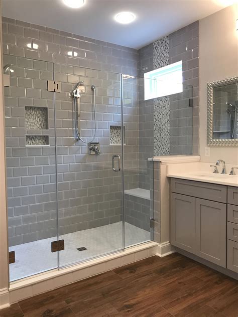 A Bathroom With A Walk In Shower Next To A White Sink And Wooden Flooring