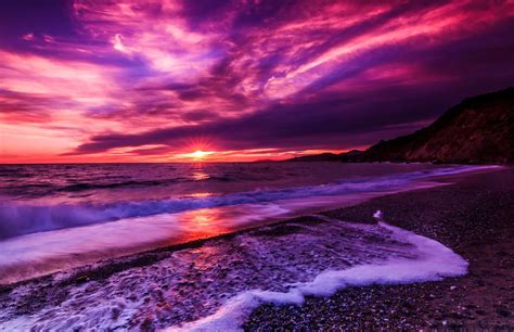Download A Purple Sunset Over The Ocean With Waves Wallpaper