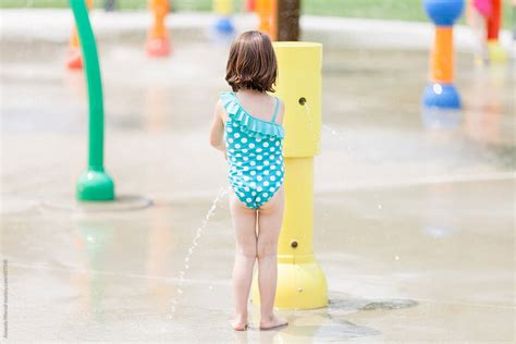Little Girl Playing In Water At A Colorful Splash Pad By Stocksy