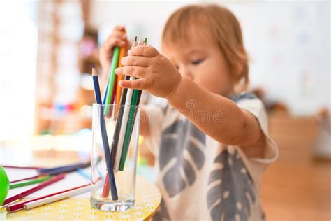 Adorable Toddler Holding Pencils Around Lots Of Toys At Kindergarten