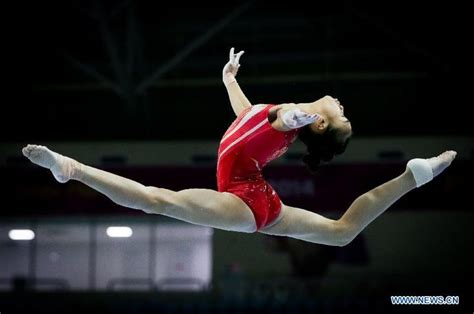 A Woman Is Performing On The Balance Beam In An Indoor Gymnastics Arena