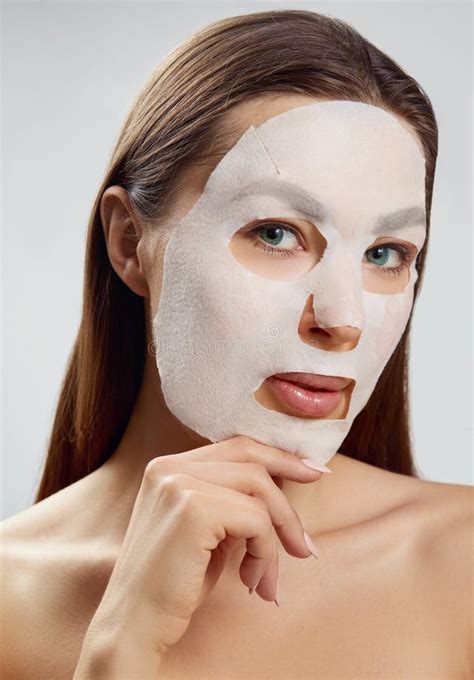 beauty face skin care woman apply a cloth moisturizing mask on face girl model with cosmetic